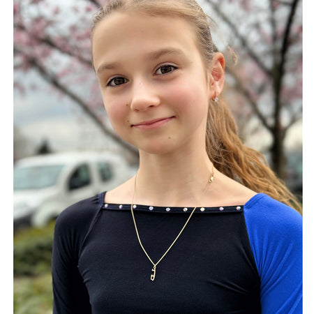 young girl with a blue and black top wearing a gold ice skate blade necklace