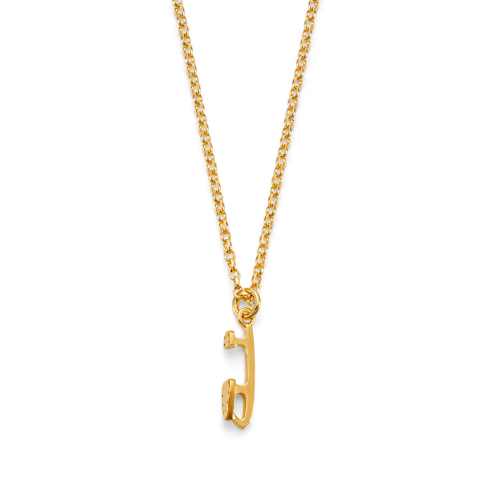 Gold necklace featuring a mini gold ice skating blade charm on a white background