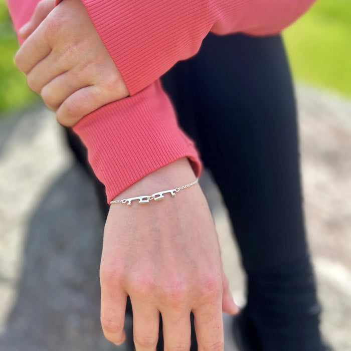 close up of a silver bracelet being worn featuring two tiny ice skate blades