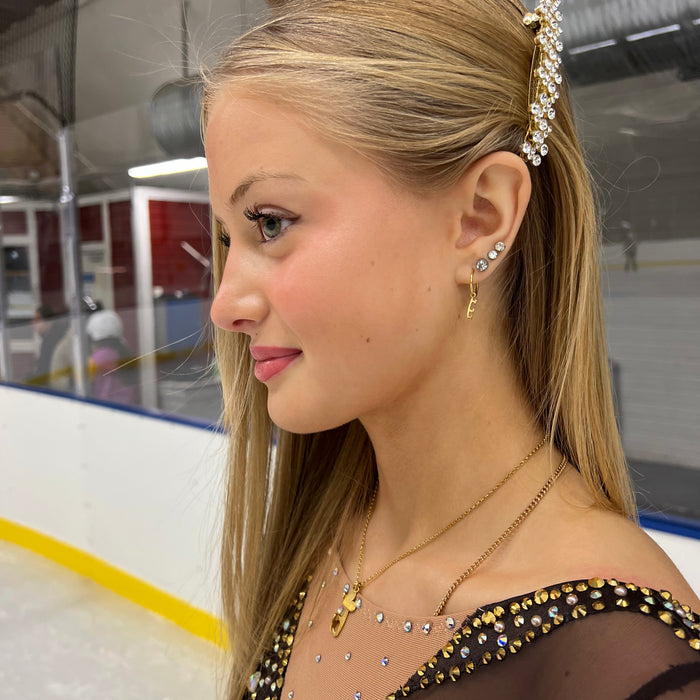 close up side view of a skater in a sparkly dress on the ice wearing gold ice skating stud hoop earrings
