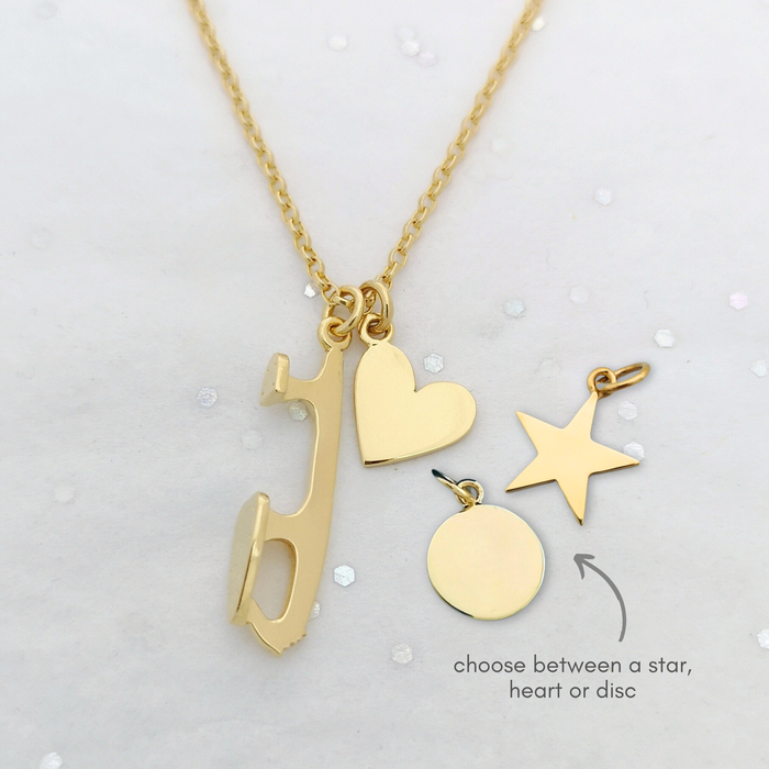 a gold plated necklace with an ice skate blade with a heart, disc and star charm