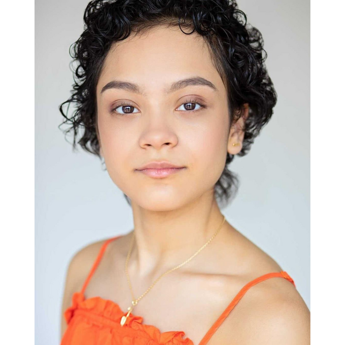 girl in an orange top wearing apersonalised gold ice skating necklace