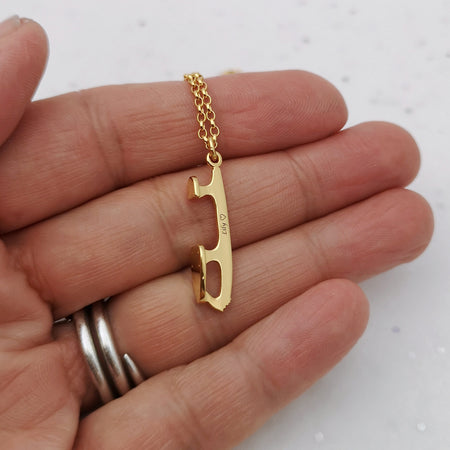 hand holding a personalised gold ice skating necklace