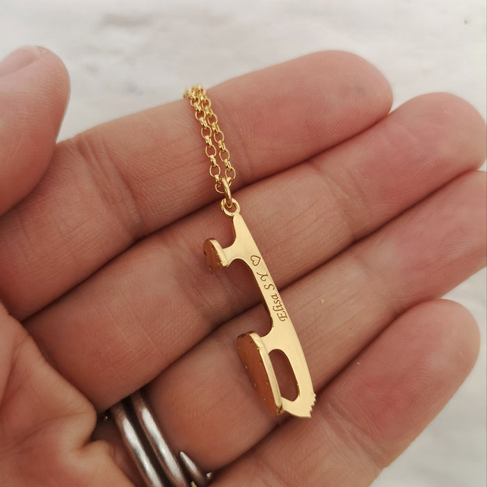 hand holding a personalised gold ice skate blade necklace