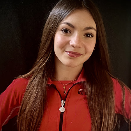 female figure skater wearing a red jacket and personalised gold ice skating necklace