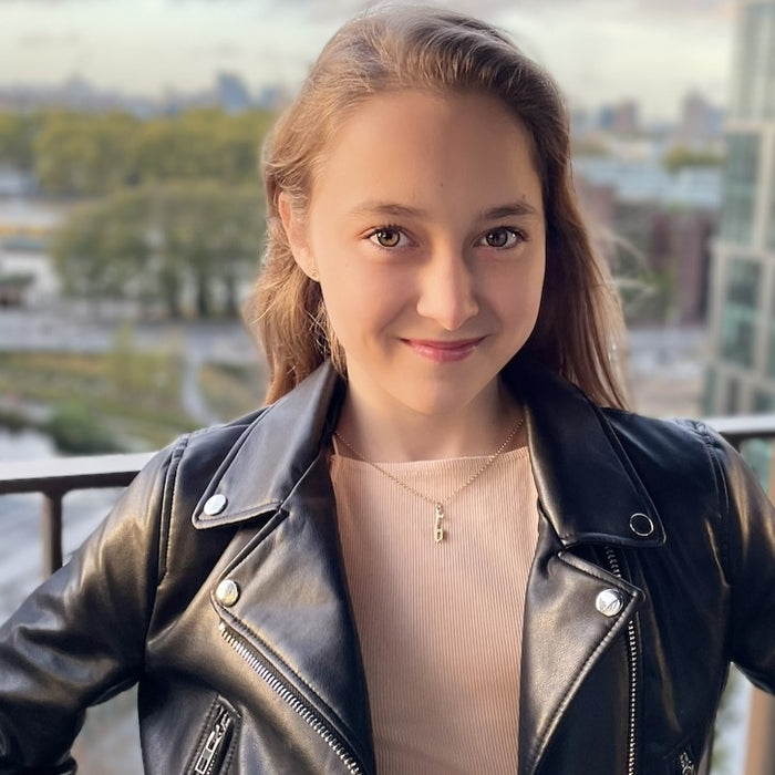 girl in a light top and a leather jacket wearing a personalised gold ice skating necklace