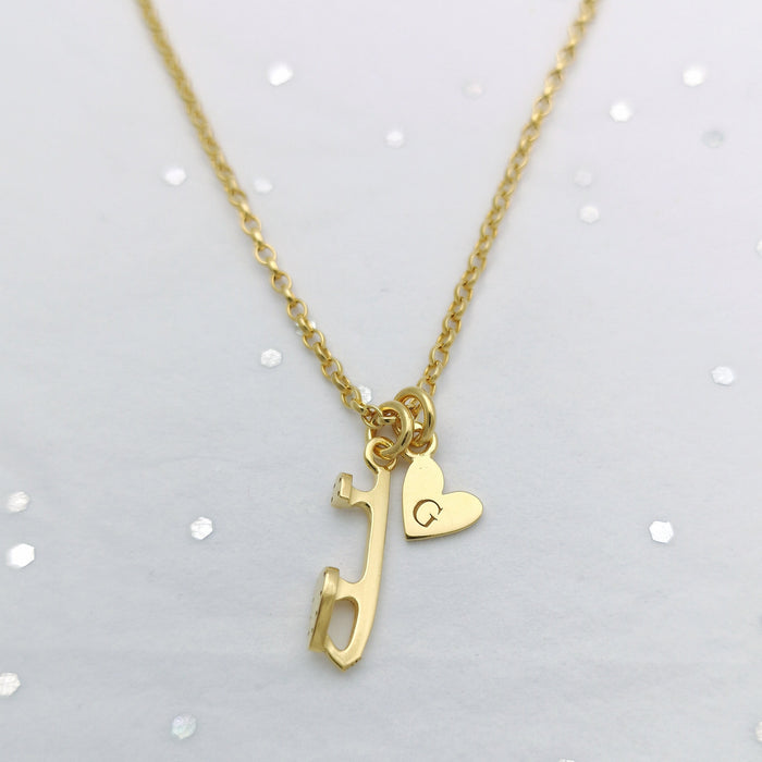gold chain necklace on a sparkly background with a gold ice skate charm and a personalised heart charm