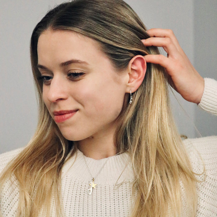 figure skater in a cream jumper wearing a silver necklace with a personalised skate blade charm and a gold star