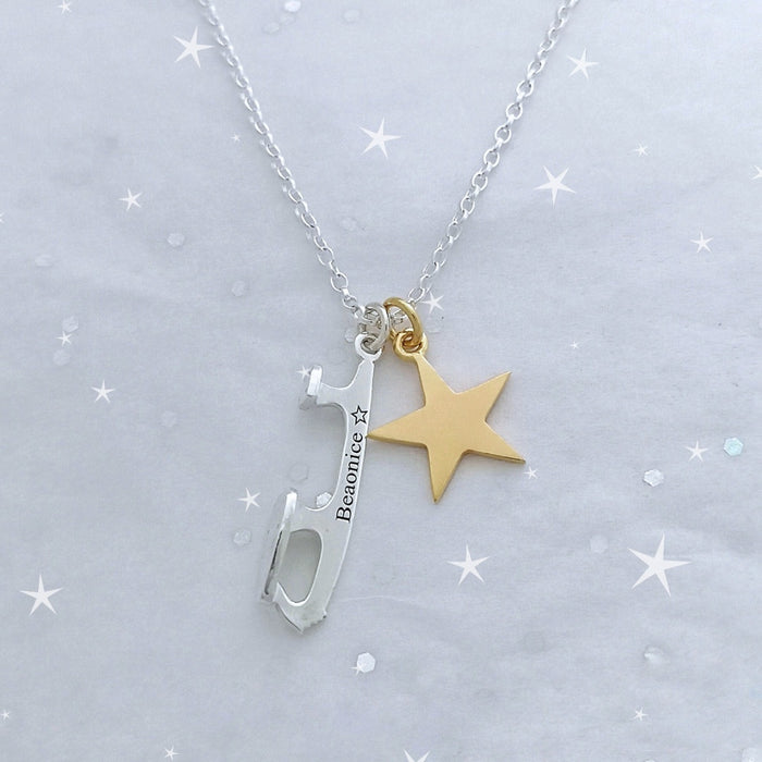 personalised necklace featuring a silver ice skating blade and a gold star on a sparkly backround