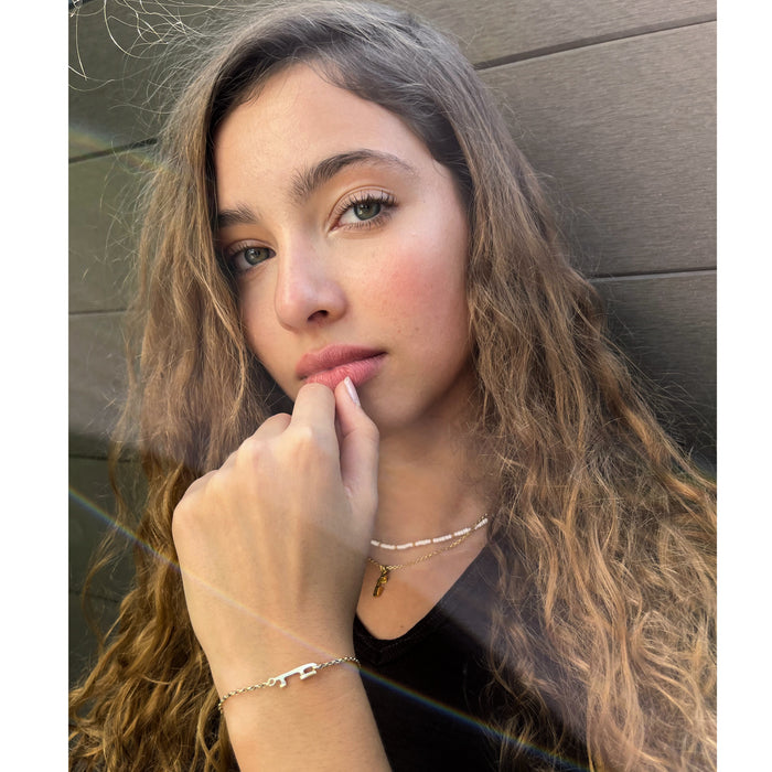 figure skater wearing a gold ice skating blade necklace and a gold bracelet featuring an ice skate blade