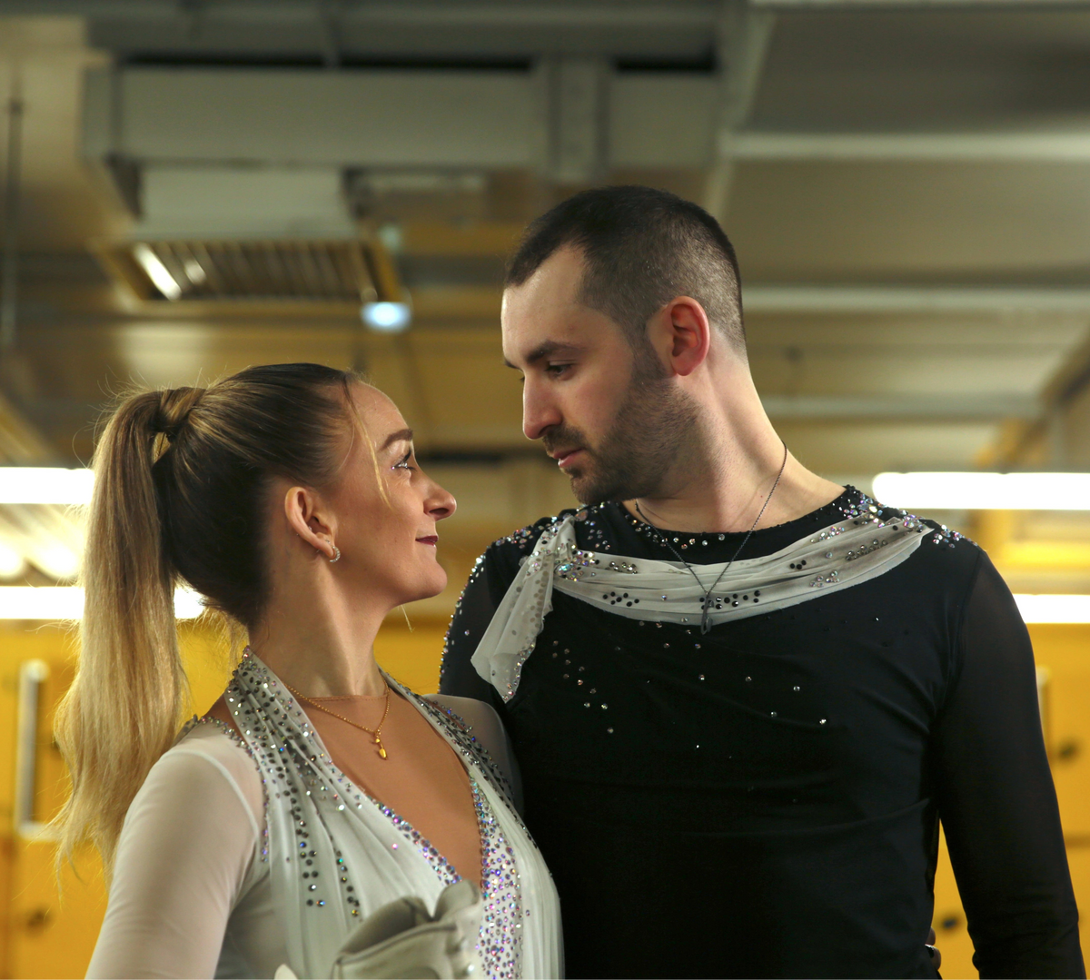 Two figure skaters in a locker room setting