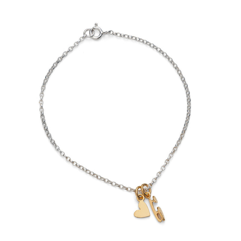fine silver chain bracelet featuring two tiny gold ice skating charms, a skate blade and a heart, on a white background