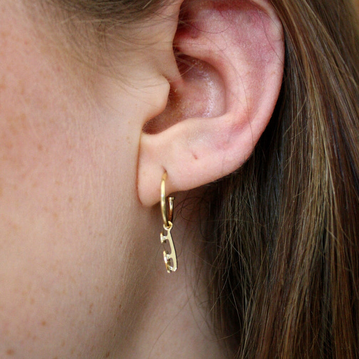 Close up image of Gold Ice Skating Stud Hoop Earrings being worn in the ear