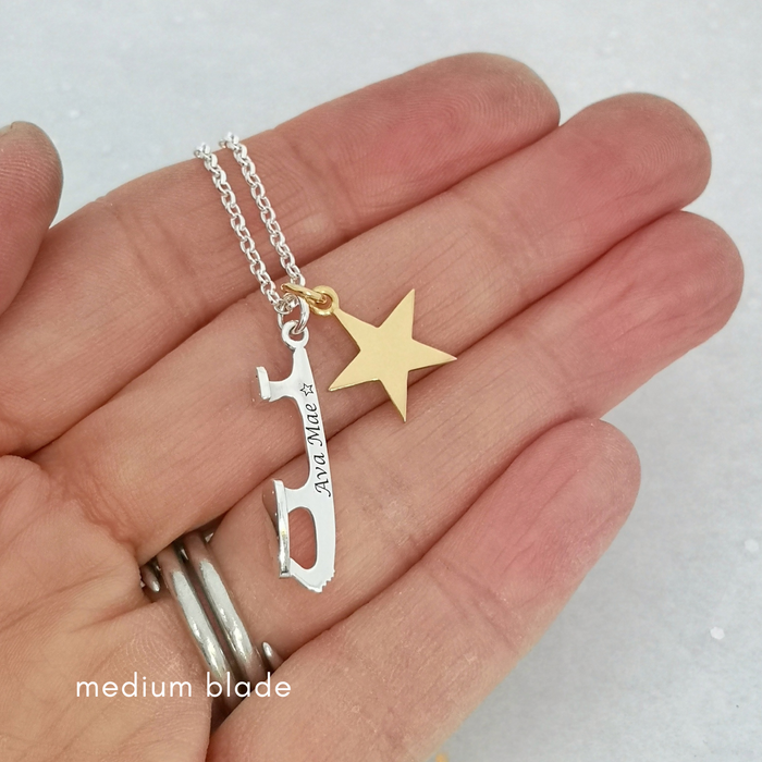 personalised silver necklace with a silver ice skate blade and a heart charm  being held in a hand