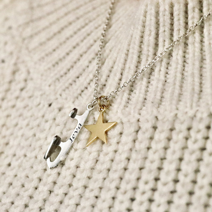 close up image of a personalised silver necklace with a silver ice skate blade and a star charm