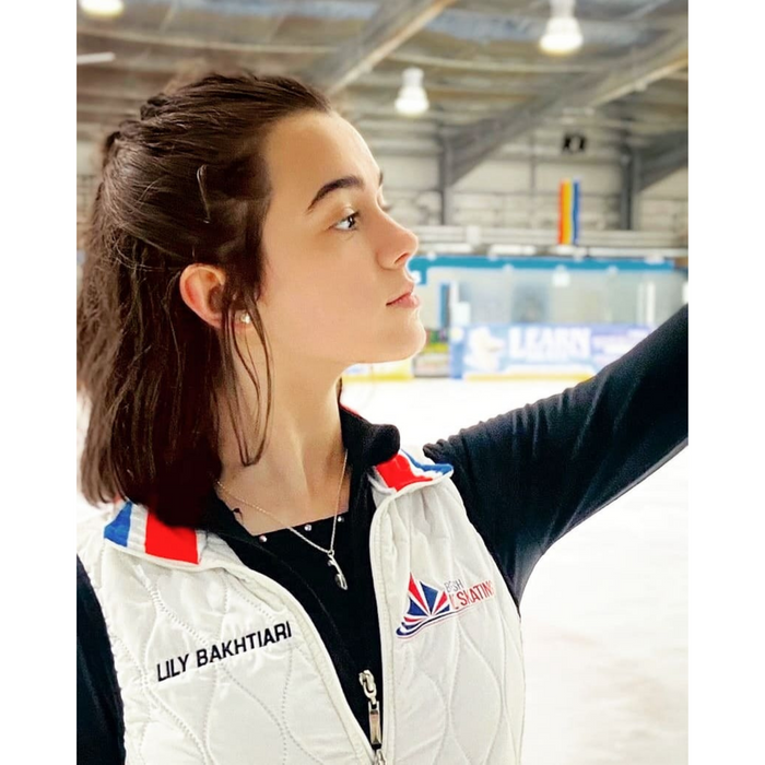 figure skater on ice wearing a white gilet and a black top
