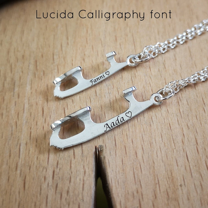two silver ice skate blade necklaces on a jewellers benchpeg, the blades are engraved with names