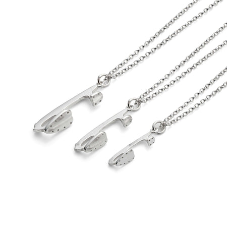 three silver ice skate blade necklaces on a white background