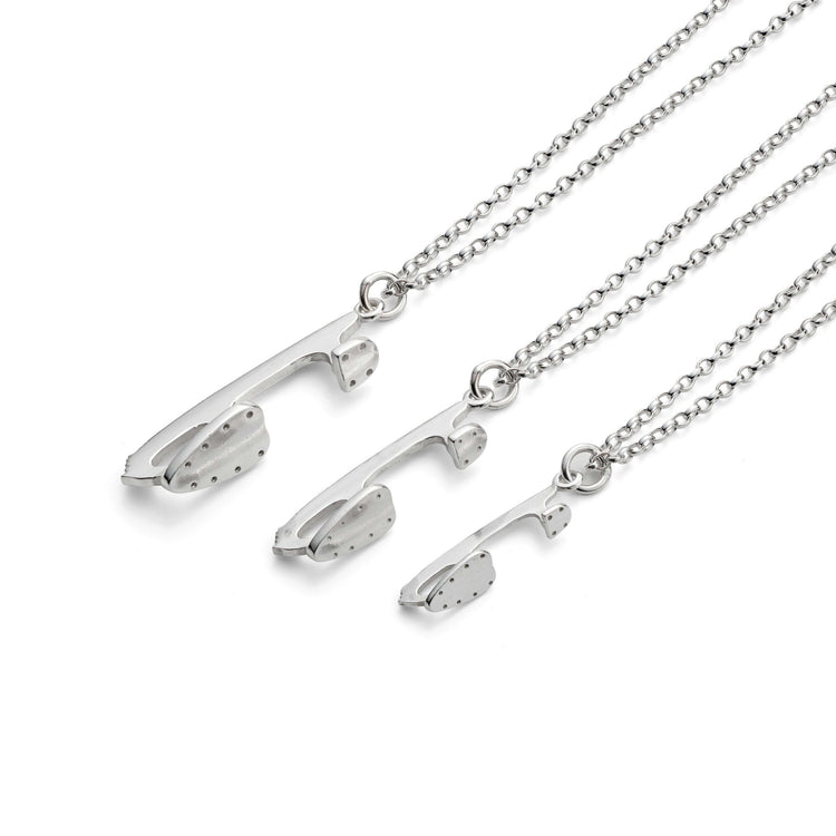 three silver ice skate blade necklaces on a white background