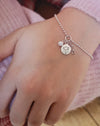 Ice Skating ball chain bracelet with three silver charms, a skate blade, disc with an engraved motto and a sarkly charm being worn on a wrist