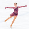 figure skater performing on ice in a sparkly dark pink dress and a gold ice skate blade necklace, her arms are out in a position and her right leg is stretched out