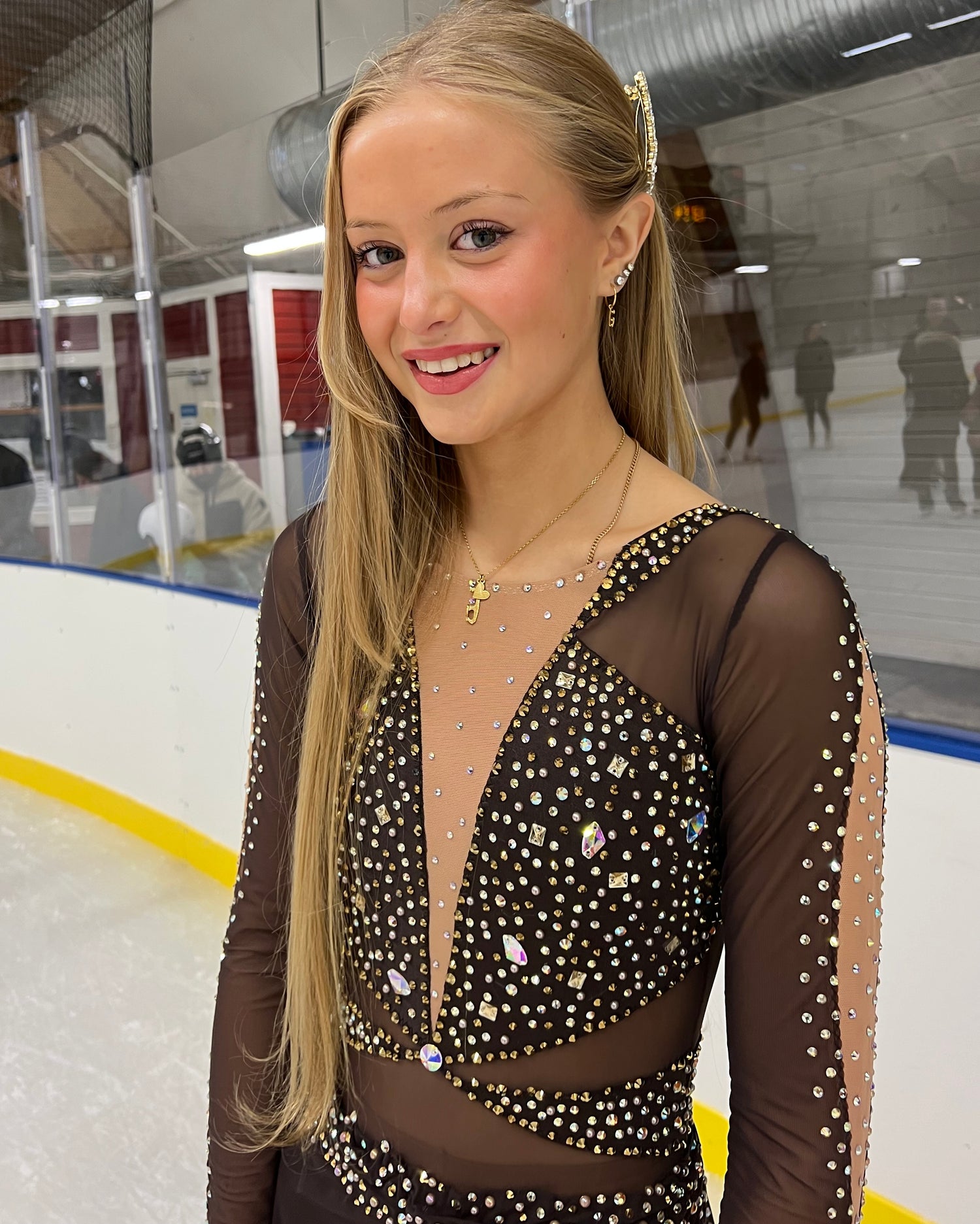 girl standing on the ice wearing a sparkly dress and a gold ice skating necklace