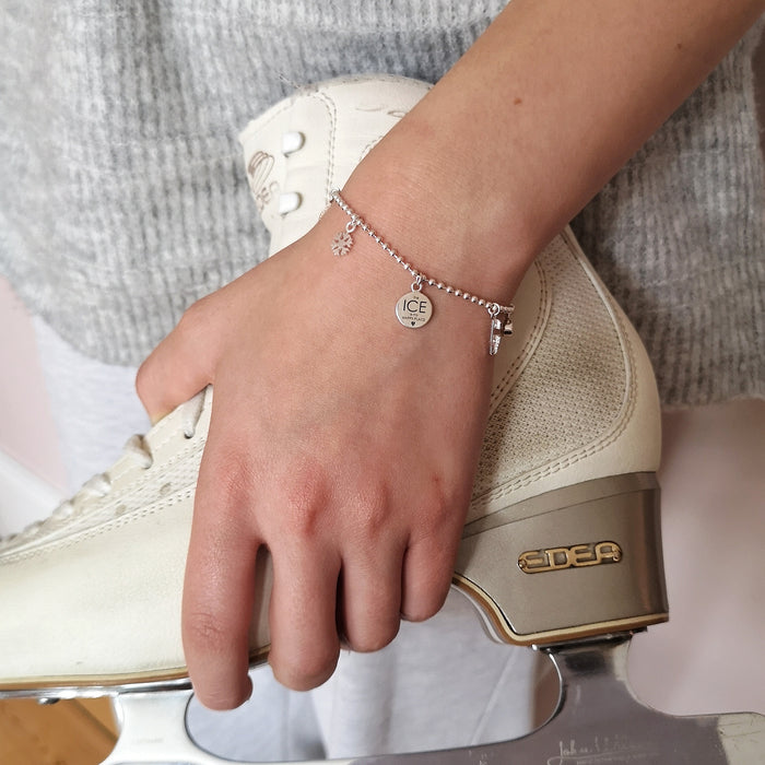 Figure skater holding an ice skating boot wearing a silver ice skating treasured charms bracelet