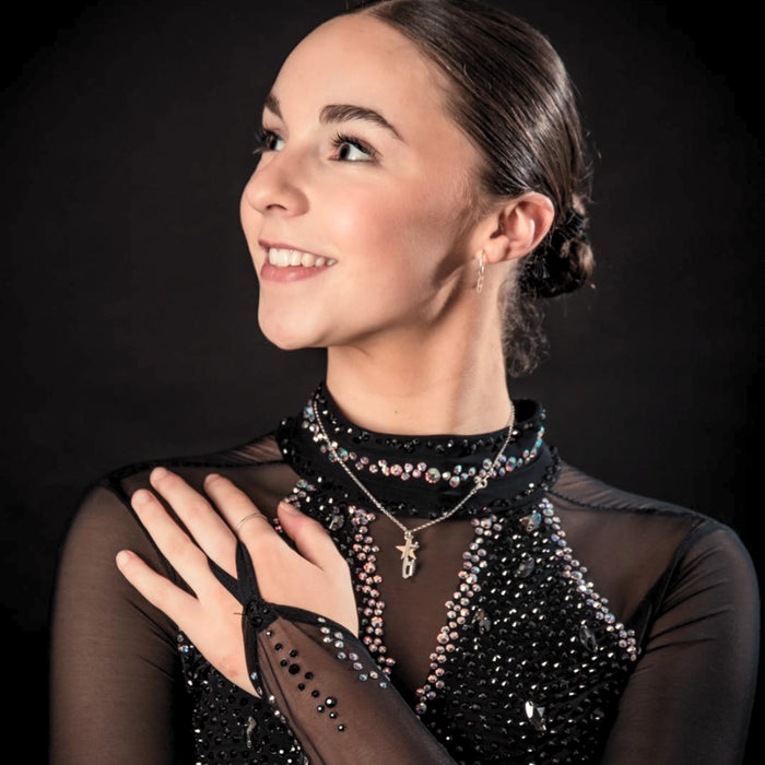 figure skater in a black sparkly dress wearing a personalised silver necklace with a silver ice skate blade and a heart charm 