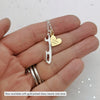 hand holding a personalised silver ice sate blade necklace with a personalised gold plated heart charm