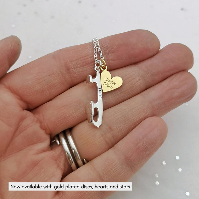 hand holding a personalised silver ice sate blade necklace with a personalised gold plated heart charm