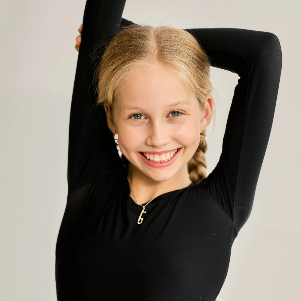 skater in a black top wearing a gold ice skate blade necklace and earrings
