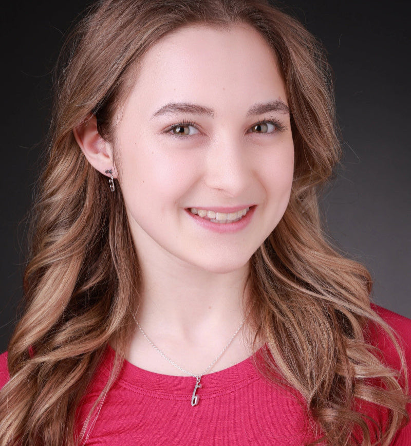Woman with long brown hair wearing a red top against a dark background