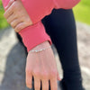close up of a silver bracelet being worn featuring two tiny ice skate blades