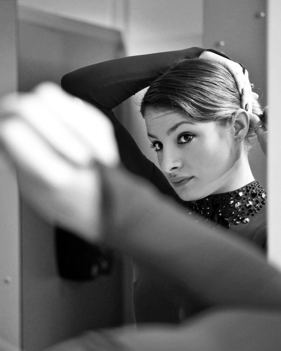 figure skater looking in a mirror and adjusting her hair before getting on ice to perform