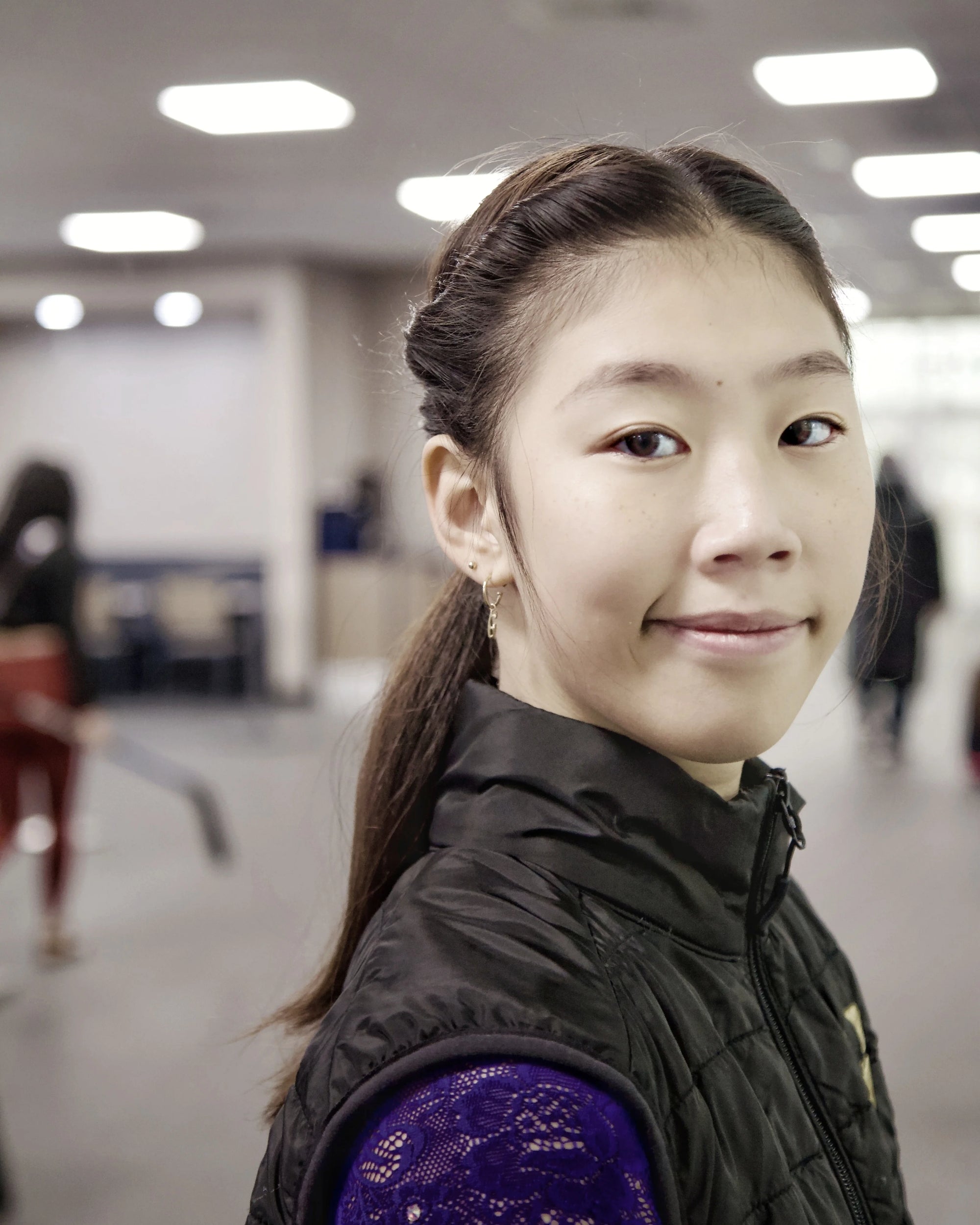 a skater near an ice rink ready to go on ice she is grinning