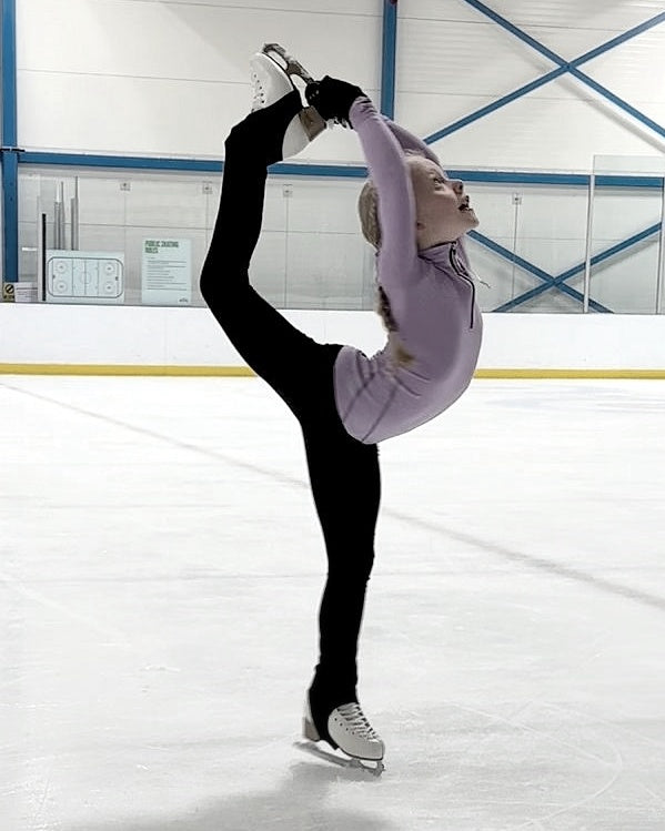 young figure skater practicing a beilmann spin on ice during training