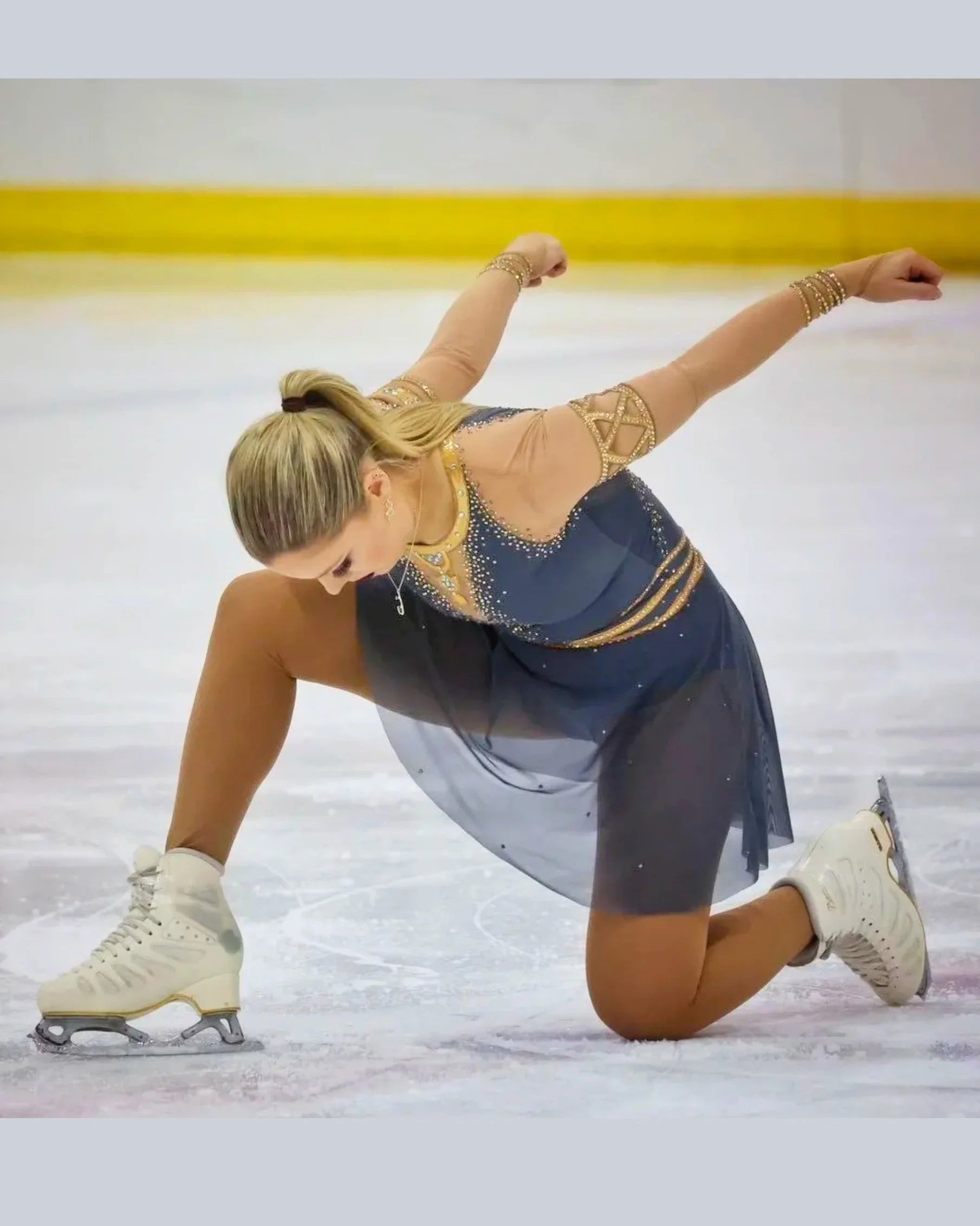 Skater in a blue and gold dress performing a routine on ice.