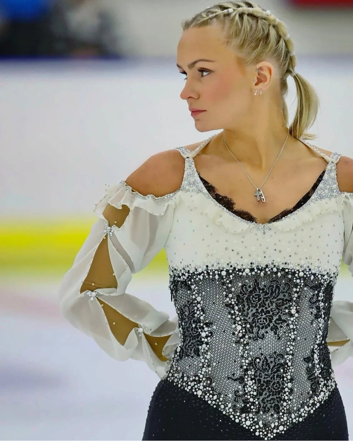 Figure skater in a sparkly costume on an ice rink waiting to start her programme with her arms behind her back in her starting position