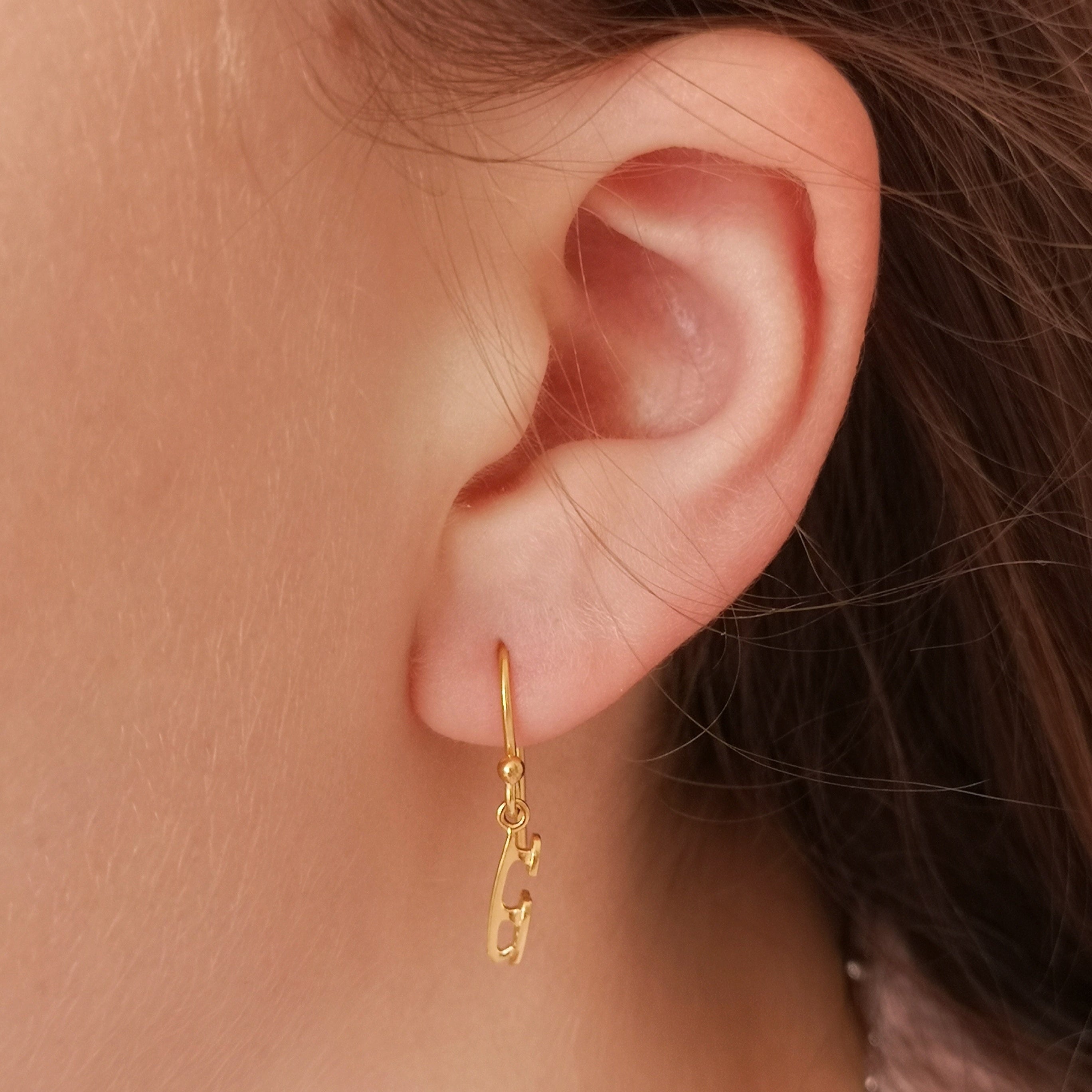 close up of a girl wearing a gold ice skate blade hook earring