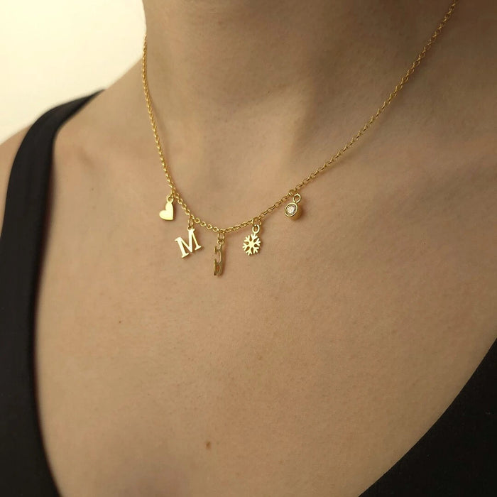 Gold necklace with various charms on a person wearing a black top.