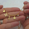 Gold necklace with charms held in a hand against a white background