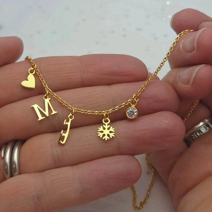 Gold necklace with charms held in a hand against a white background