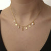 Gold necklace with various charms on a person wearing a black top.