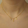 Gold necklace with three charms on a person's neck