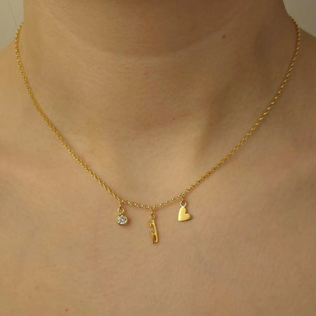 Gold necklace with three charms on a person's neck