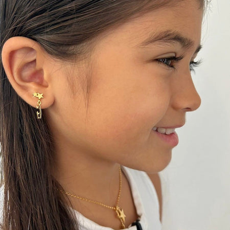 close up image of skater wearing gold ice skate blade and star stud earrings