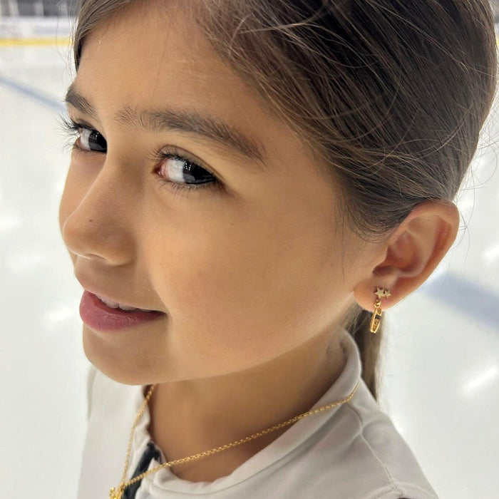 close up image of skater wearing gold ice skate blade and star stud earrings