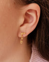 close up of girl in a pink sweater wearing a gold ice skate blade and star earring