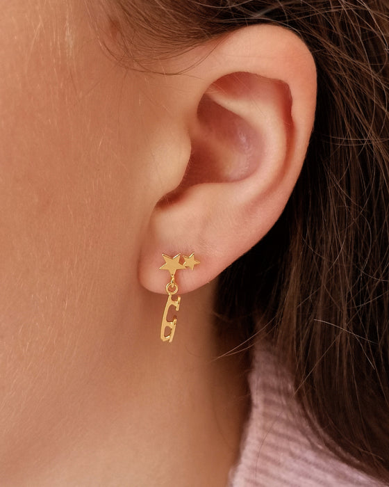 close up of girl in a pink sweater wearing a gold ice skate blade and star earring