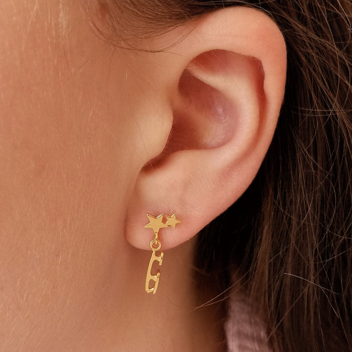 close up of girl in a pink sweater wearing a gold ice skate blade and star earring